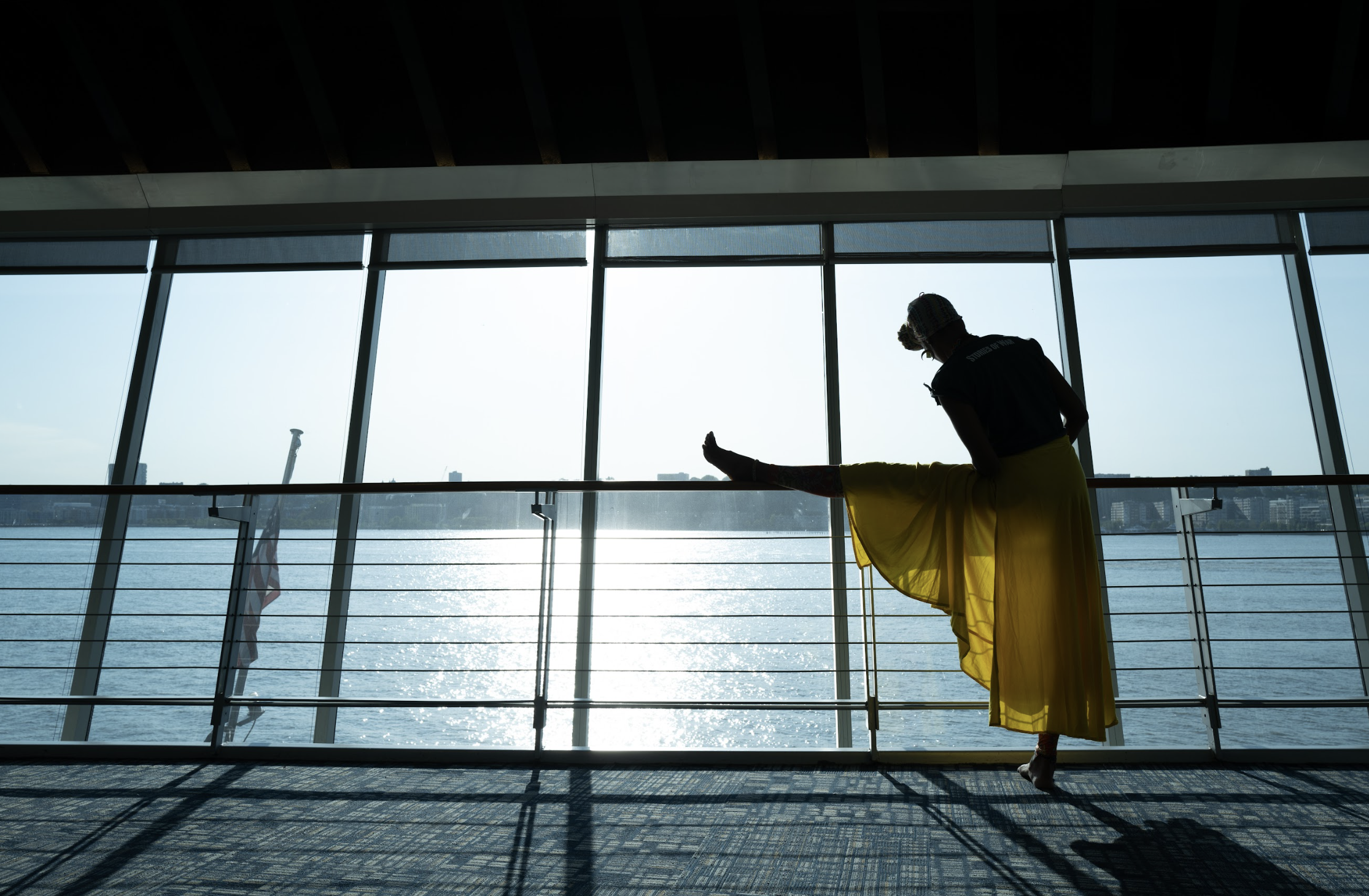 A woman stretches on a ballet bar in front of a window overlooking New York's Hudson River.