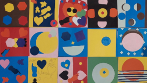 Colorful artwork using shapes such as hearts, hexagons, squares, a silhouette of a hand pointing, and more. The artwork is a series of individual square pieces assembled to make one mural.