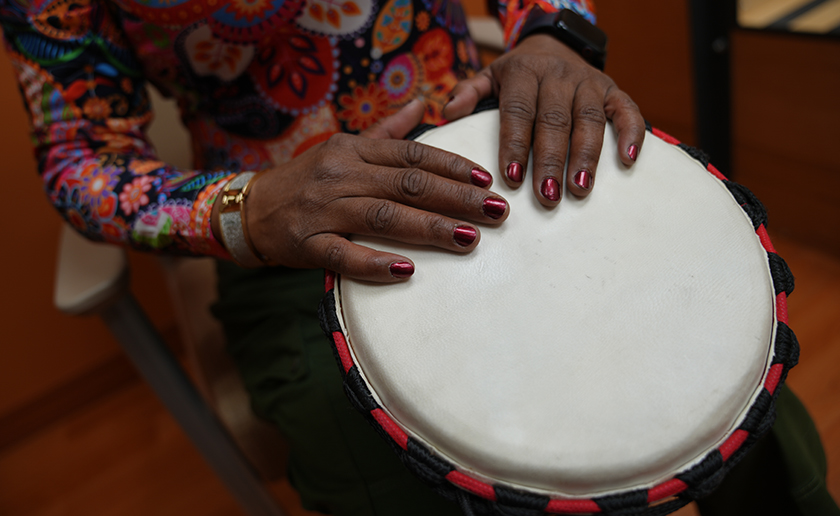 Image of a black woman's hands on a djembe drum head.
